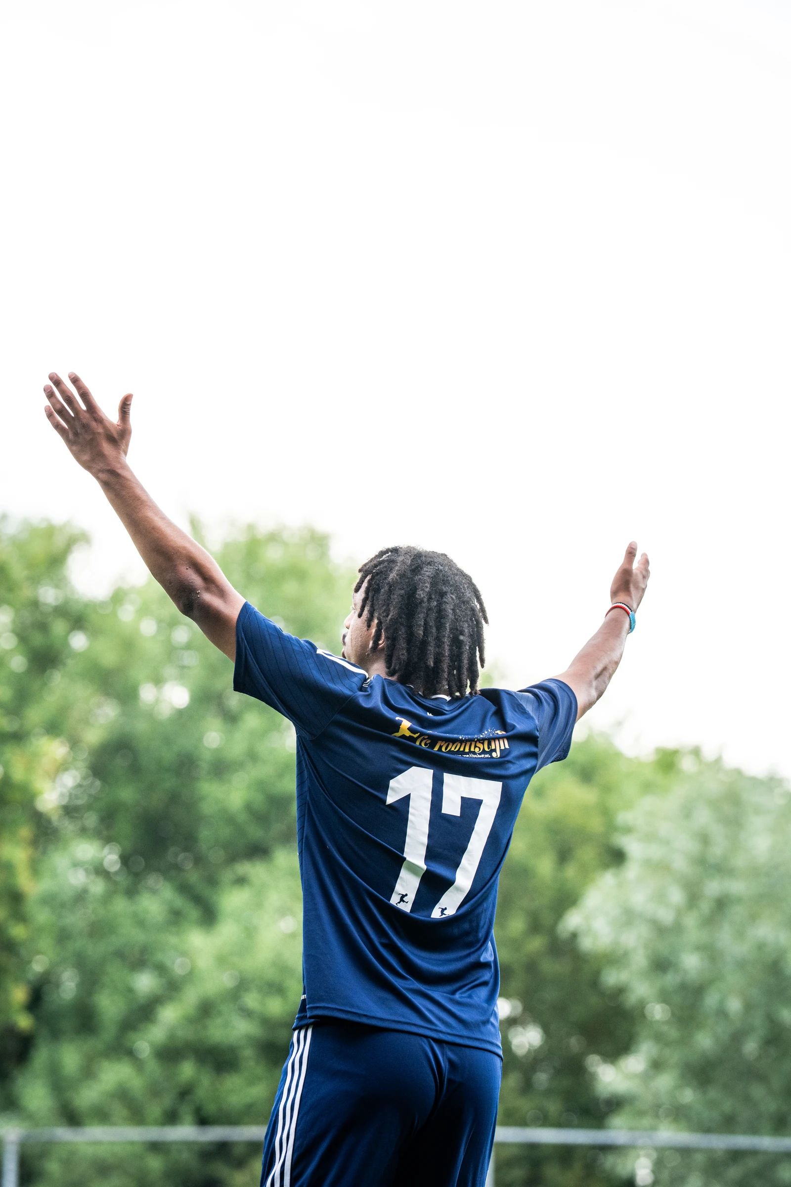 Een speler met nummer 17 op de rug steekt zijn armen in de lucht