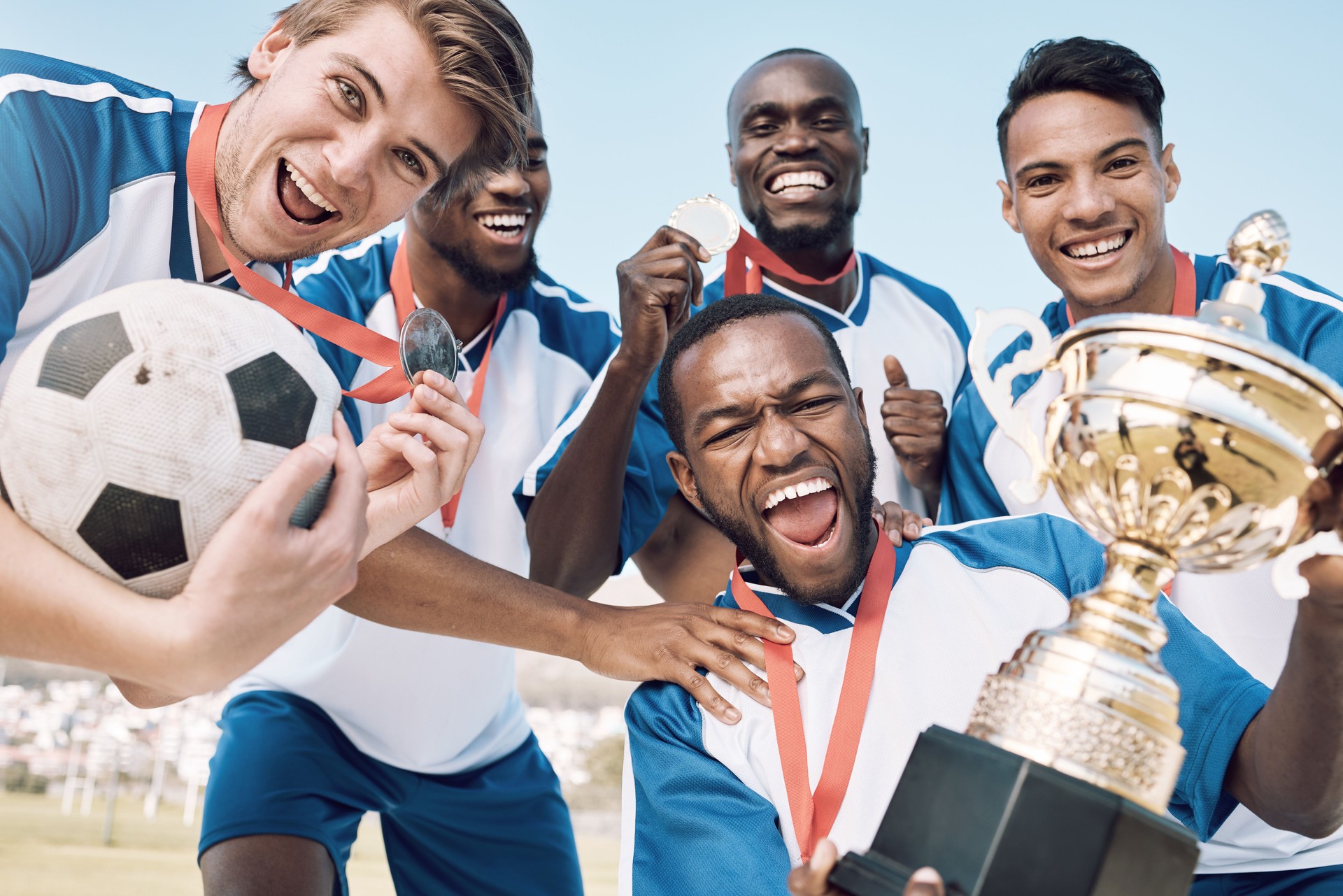 Soccer, trophy and men team winning portrait at sports competition or game with teamwork on a field. Football champion group people with medal or prize for goal, performance and fitness achievement
